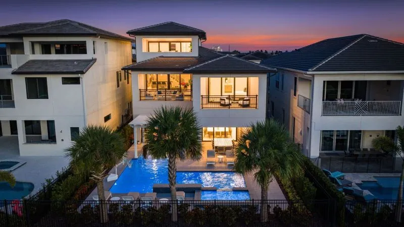 Aerial rear view of Orlando luxury villa with pool, palm trees and warm sunset glow