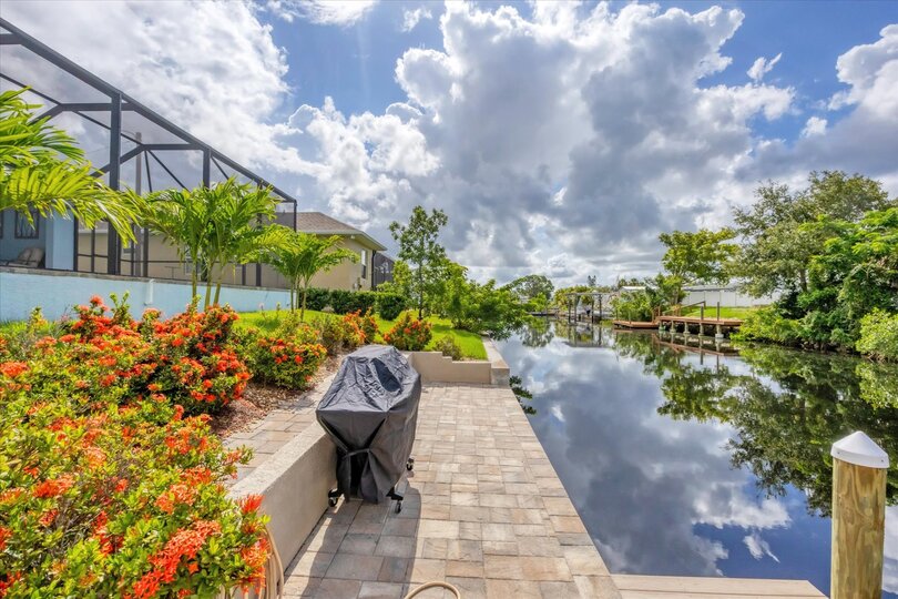 BBQ grill in backyard with path leading to boat dock and canal