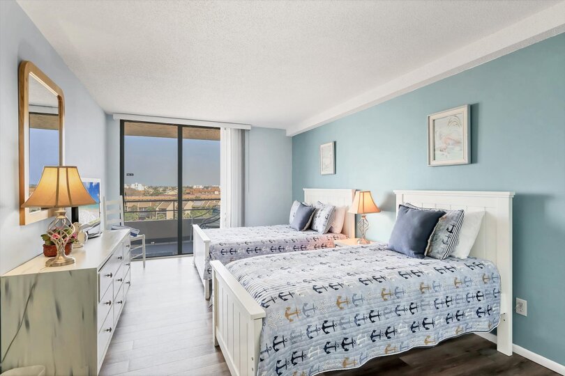 Guest Bedroom with one Queen Bed, one twin bed, balcony access, and a 32" TV