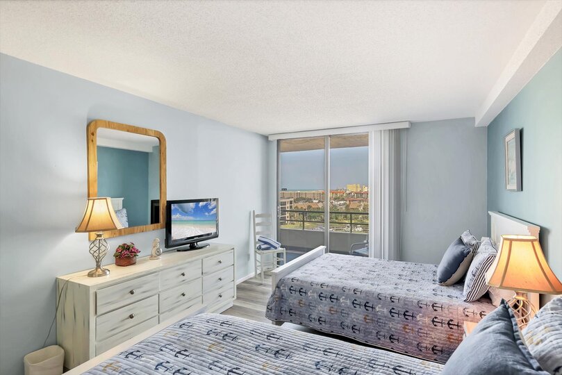 Guest Bedroom with one Queen Bed, one twin bed, balcony access, and a 32" TV