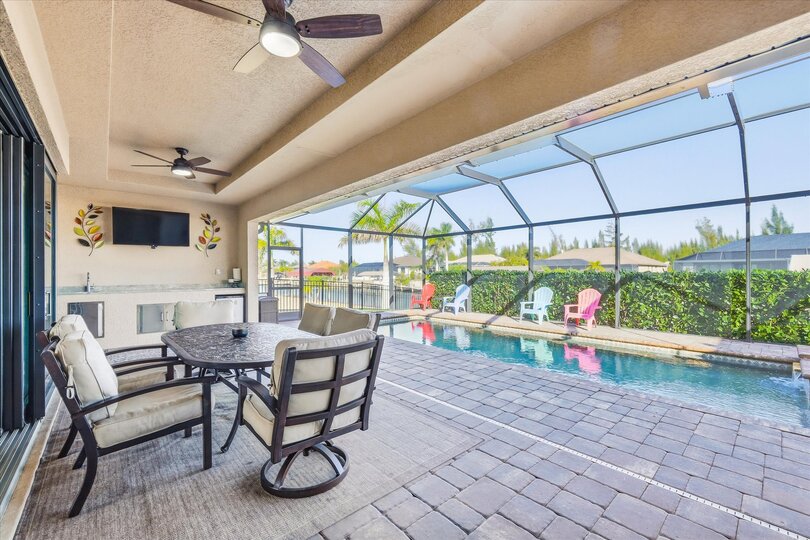 Large outdoor living area overlooking the sparkling pool and canal. Great for entertaining. Features a dining table that seats 6, BBQ grill, outdoor kitchen, Conversation furnite set, and 43" Smart TV