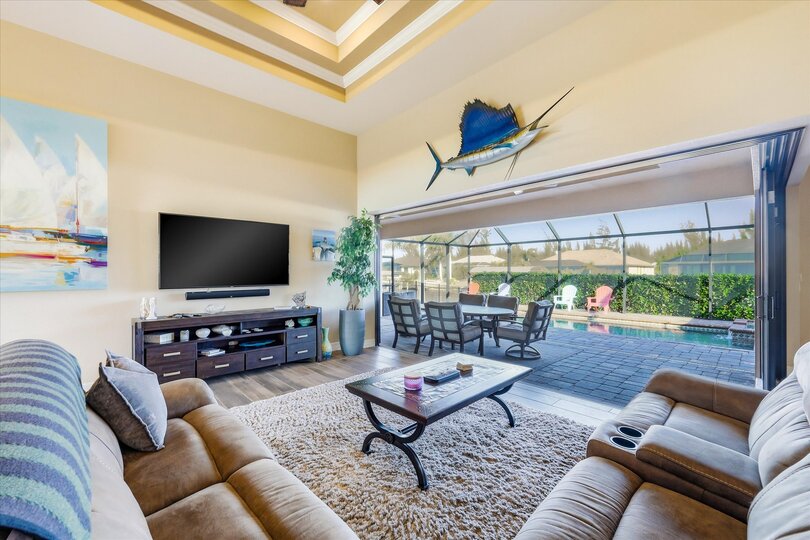 Living room overlooking the pool with comfy seating and 70-inch Smart TV