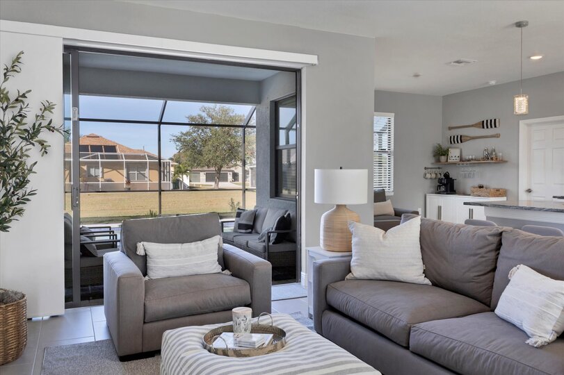 Living room overlooks the pool and features comfy seating and a 55" Smart TV