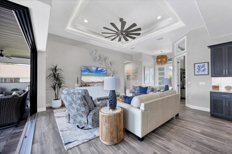 Living room overlooking the sparkling pool and canal beyond. Living room features lots of comfy seating and 75-inch Smart TV