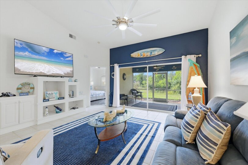 Large living space includes patio access overlooking the pond, and 75-inch Smart TV