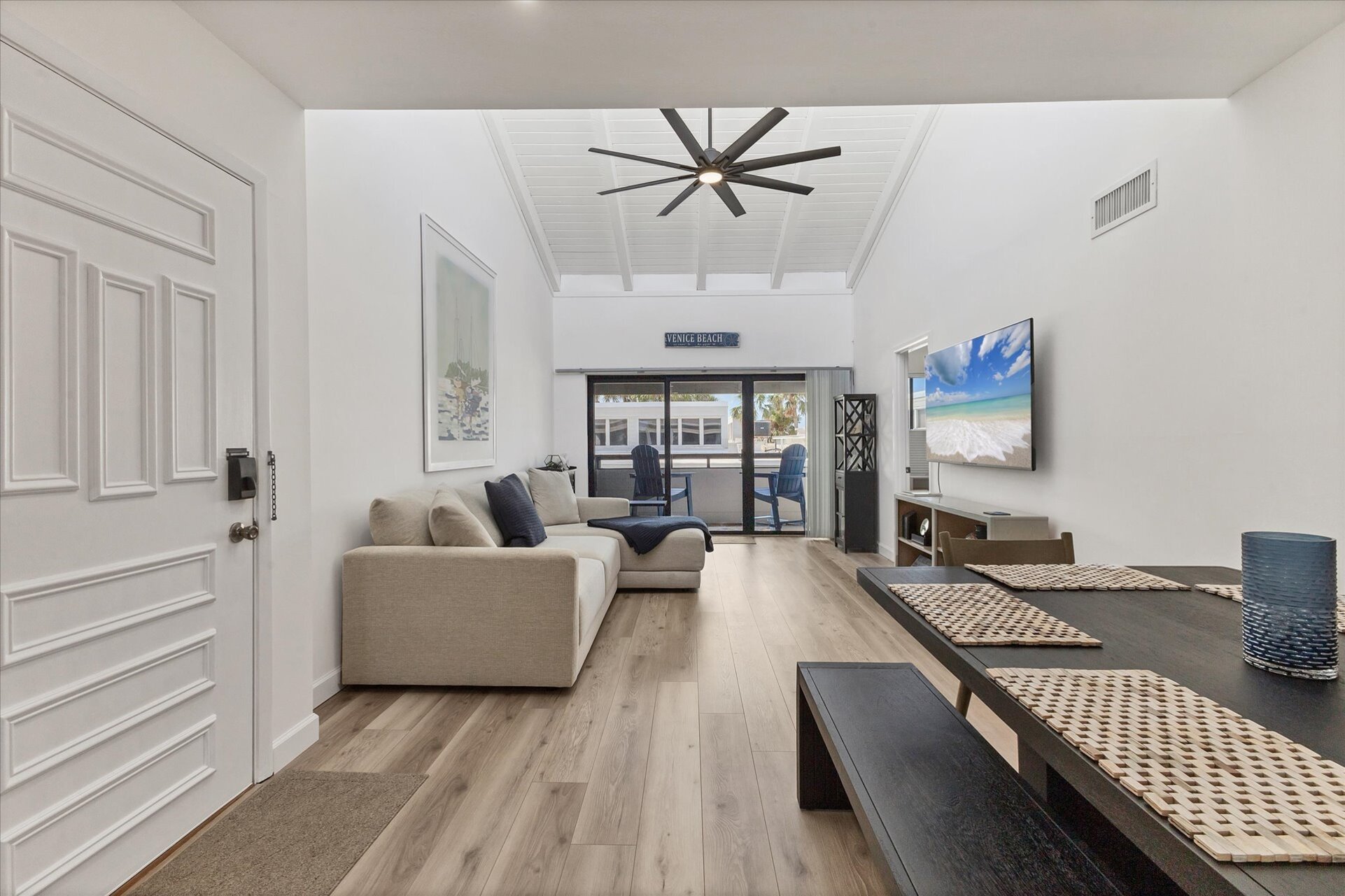 Bright, open living/dining space. Living room features comfy seating, a 65-inch Smart TV and balcony access